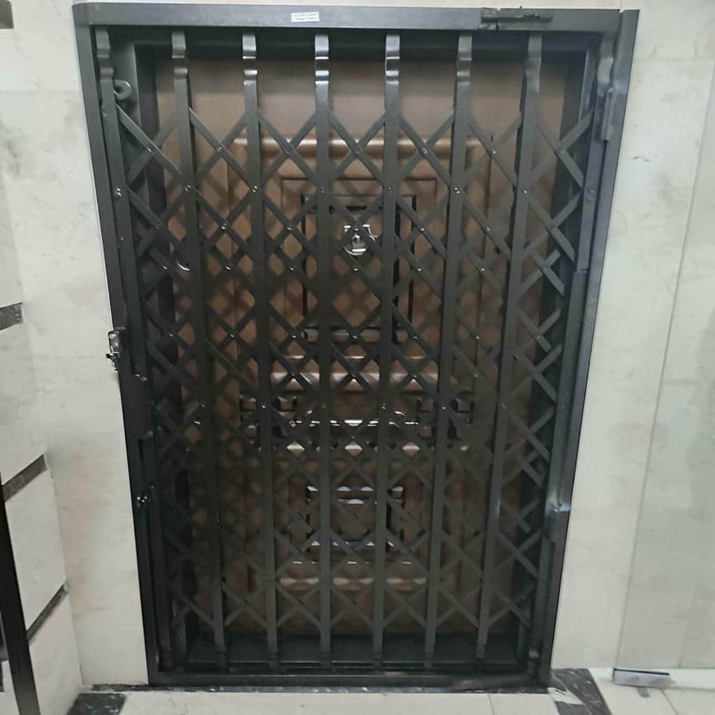 حفاظ درب آکاردئونی خاکستری کنار درب چوبی