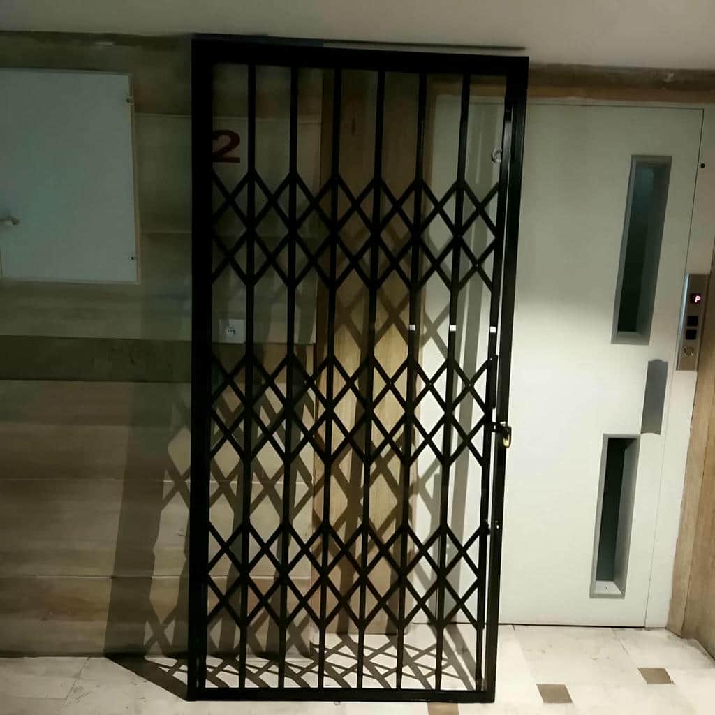 حفاظ درب آکاردئونی خاکستری کنار ورودی کرمانشاه